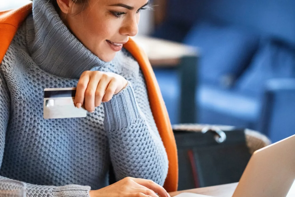 Young businesswoman relaxing on coffee break and using credit card and laptop for online shopping.