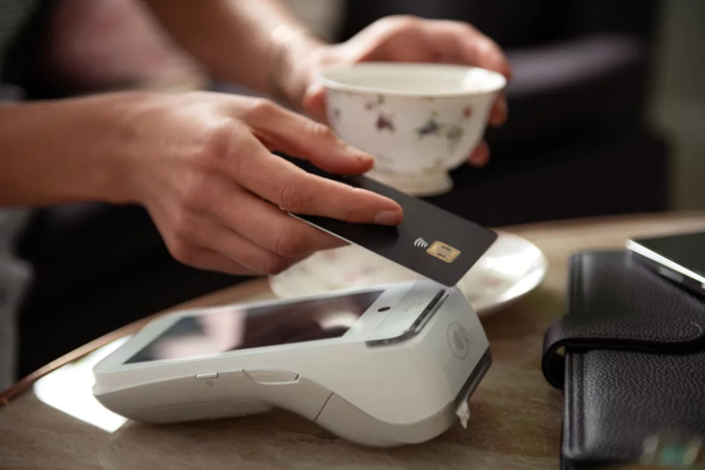 Contactless payment concept, female customer holding credit card near NFC technology on counter