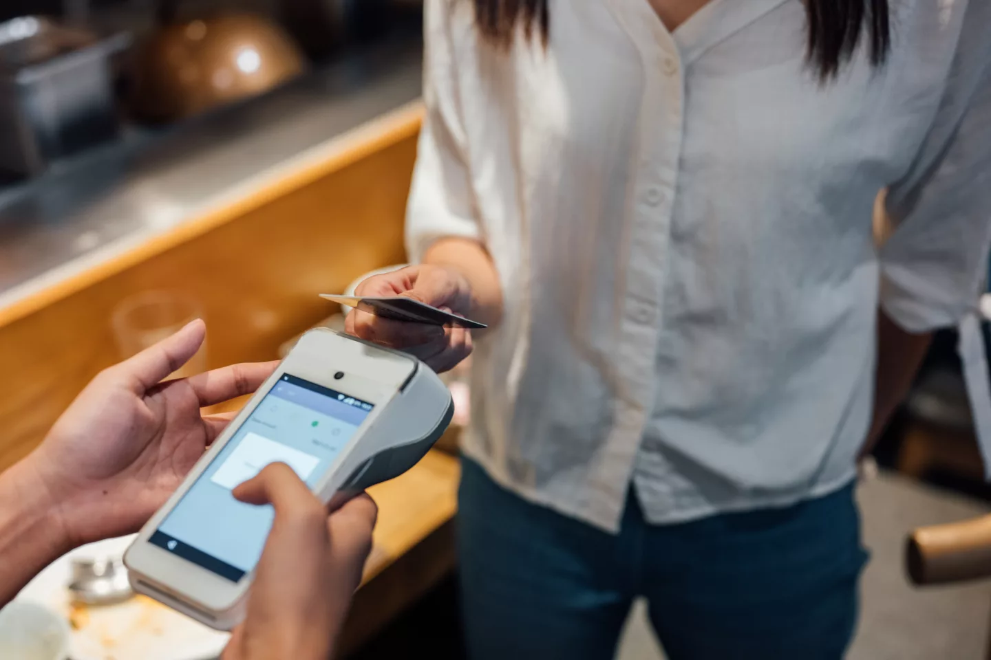 Unrecognizable woman using credit card and making a contactless payment at cafe.