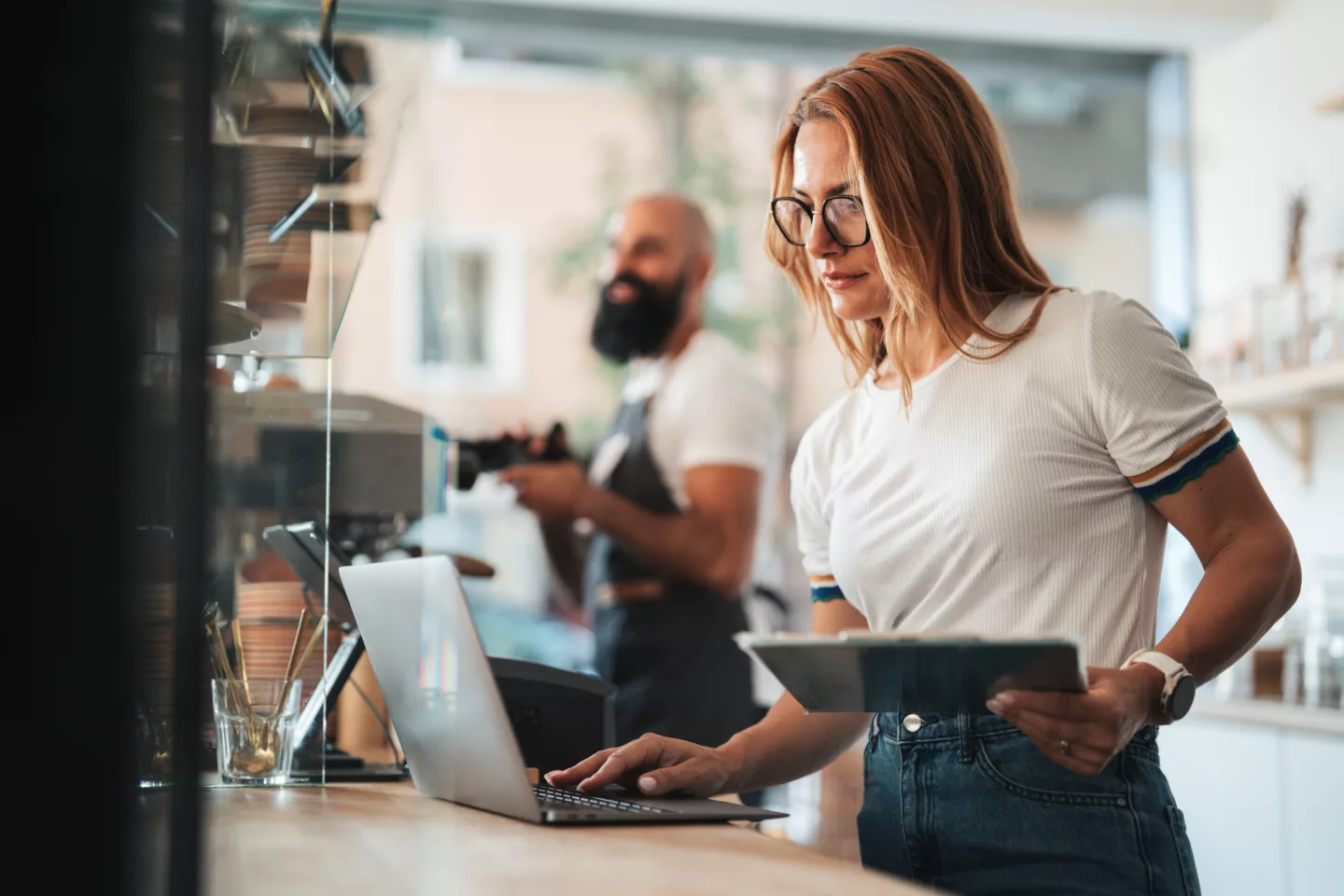Small business owner in a cafe reviewing online orders. Concept of digital business management, food delivery coordination, and modern cafe operations